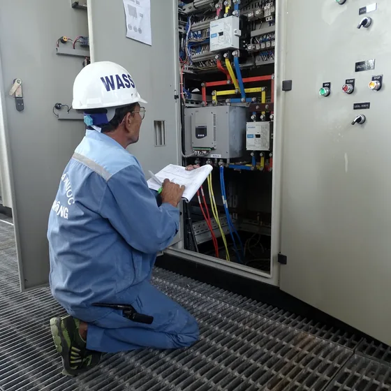 Técnico de segurança conferindo um painel elétrico com prancheta na mão